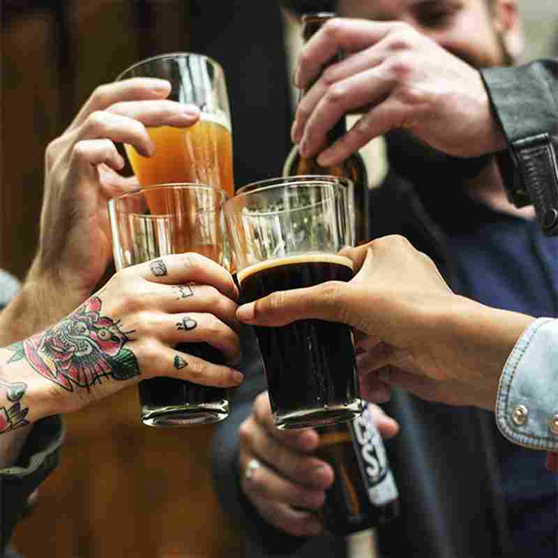 A group of people holding glasses with beer in them.